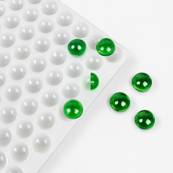 Finished emerald green gummy samples beside a commercial silicone mold during post-production handling