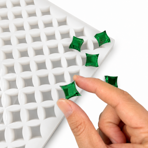 Hand pressing a finished emerald green star gummy in a flexible silicone gummy mold