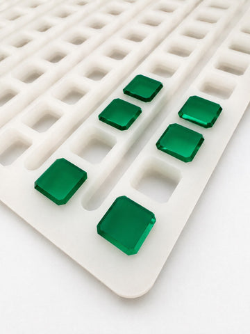 Angled view of a 2.3mL universal depositor cube gummy mold with 136 cavities and smooth emerald green cube gummies on a white background